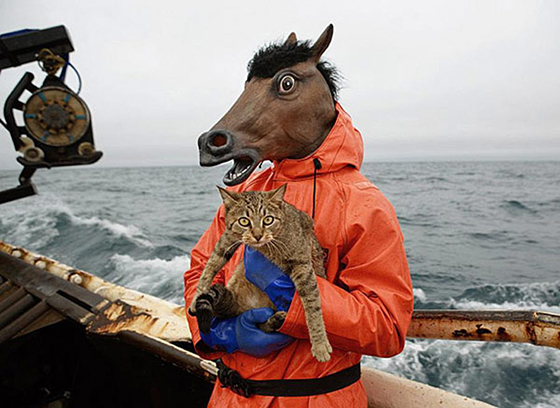 Человек в маске лошади с котом на рыболовецком судне